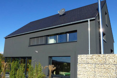 Zweistöckiges Haus mit Betonfassade, grauer Fassadenfarbe und Satteldach in Sonstige
