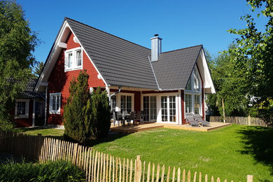 Immagine della villa piccola rossa scandinava a un piano con rivestimento in legno, tetto a capanna e copertura in tegole