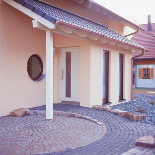 Imagen de fachada de casa amarilla, mediterránea, de dos plantas, con revestimiento de estuco, tejado a dos aguas y tejado de teja de barro