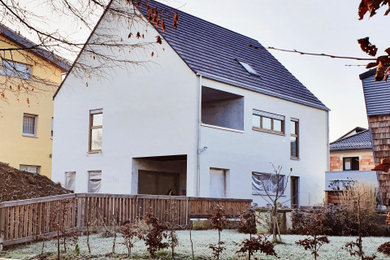 Ejemplo de fachada de casa de tamaño medio de dos plantas con revestimiento de estuco, tejado a dos aguas y tejado de teja de barro