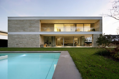 Diseño de fachada beige contemporánea grande de dos plantas con tejado plano y revestimiento de piedra