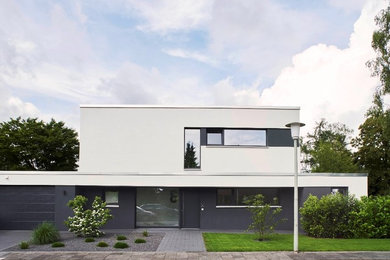 Zweistöckiges, Mittelgroßes Modernes Einfamilienhaus mit Putzfassade, weißer Fassadenfarbe und Flachdach in Düsseldorf