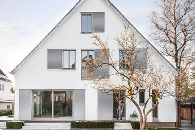 Großes, Dreistöckiges Skandinavisches Haus mit weißer Fassadenfarbe und Satteldach in München