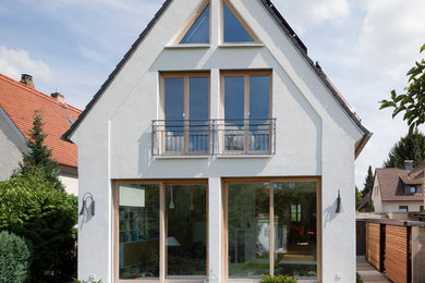 Imagen de fachada blanca clásica renovada pequeña de dos plantas con revestimiento de estuco y tejado a dos aguas