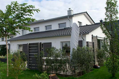 Diseño de fachada blanca contemporánea grande de dos plantas con revestimiento de estuco y tejado a dos aguas