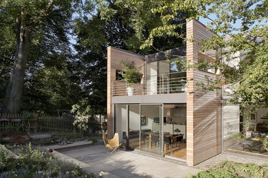 Photo of a medium sized and brown contemporary two floor house exterior in Dortmund with a flat roof and wood cladding.