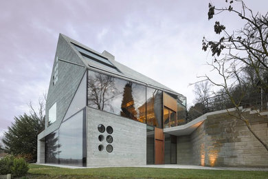 Ejemplo de fachada gris actual de tamaño medio de tres plantas con tejado a dos aguas y revestimiento de hormigón