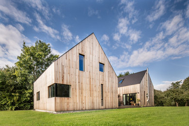 Cette photo montre une grande façade de maison marron tendance en bois à un étage avec un toit à deux pans.