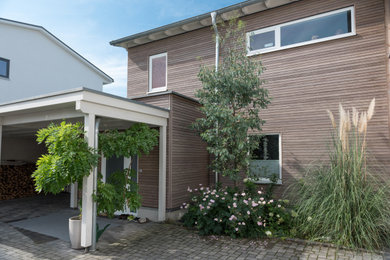 Landhausstil Holzfassade Haus mit brauner Fassadenfarbe und Flachdach in Köln