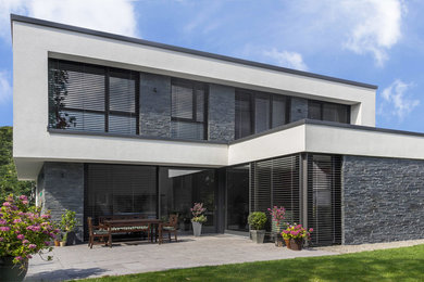 Mittelgroßes, Zweistöckiges Modernes Einfamilienhaus mit Putzfassade, weißer Fassadenfarbe und Flachdach