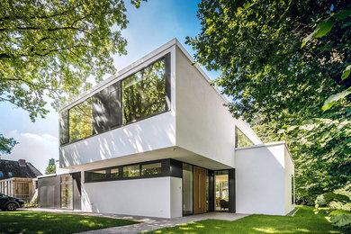 Modelo de fachada de casa blanca contemporánea grande de dos plantas con revestimiento de estuco y tejado plano