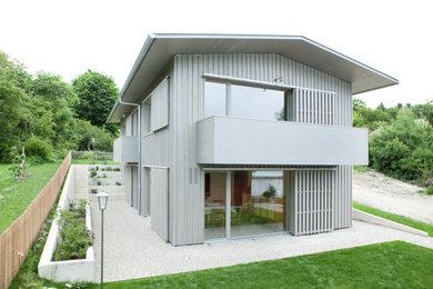 Ejemplo de fachada de casa gris actual con revestimiento de madera y tejado de metal