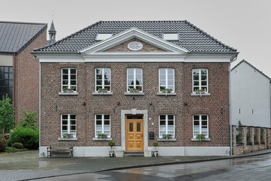 Großes, Dreistöckiges Landhausstil Haus mit Backsteinfassade, roter Fassadenfarbe, Satteldach und Ziegeldach in Düsseldorf