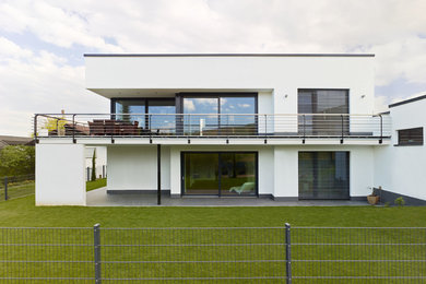 Diseño de fachada de casa blanca minimalista de tamaño medio de dos plantas con revestimiento de estuco, tejado plano y tejado de varios materiales