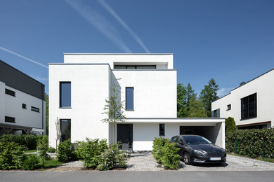 Mittelgroßes, Dreistöckiges Modernes Einfamilienhaus mit Putzfassade, weißer Fassadenfarbe und Flachdach in Berlin