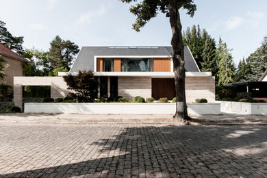 Cette photo montre une très grande façade de maison beige tendance en pierre à deux étages et plus avec un toit en appentis et un toit en shingle.