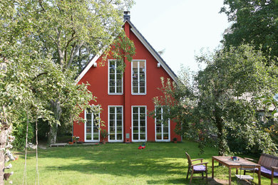 Mittelgroßes, Zweistöckiges Landhaus Einfamilienhaus mit Putzfassade, roter Fassadenfarbe, Satteldach und Ziegeldach in Berlin