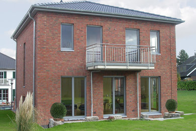 Idées déco pour une façade de maison rouge classique en brique à un étage avec un toit à quatre pans, un toit en tuile et un toit gris.
