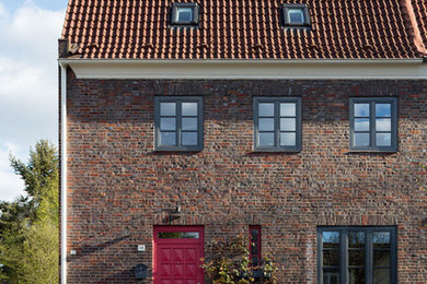 Imagen de fachada de casa bifamiliar roja clásica de tamaño medio de dos plantas con revestimiento de ladrillo, tejado a dos aguas y tejado de teja de barro
