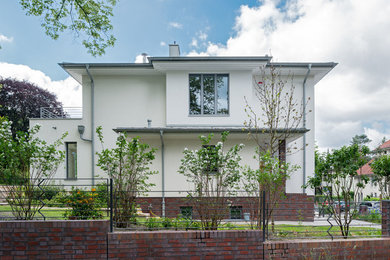 Mittelgroßes, Dreistöckiges Modernes Einfamilienhaus mit Mix-Fassade, weißer Fassadenfarbe und Flachdach in Berlin