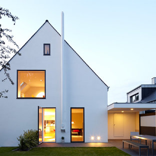 Esempio della facciata di una casa unifamiliare bianca scandinava a tre piani di medie dimensioni con tetto a capanna e rivestimento in stucco