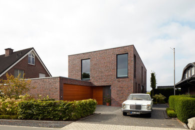 Cette photo montre une grande façade de maison marron moderne en brique à un étage avec un toit plat.