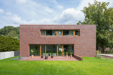 Esempio della facciata di una casa contemporanea a due piani di medie dimensioni con rivestimento in mattoni e tetto piano