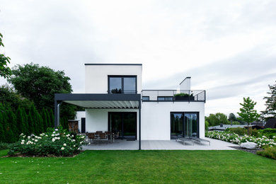 Mittelgroßes, Zweistöckiges Modernes Einfamilienhaus mit Putzfassade, weißer Fassadenfarbe und Flachdach in Sonstige
