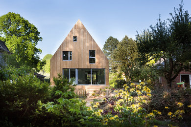 Exemple d'une grande façade de maison beige tendance en bois à un étage.