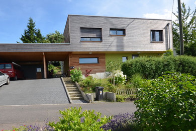 Ejemplo de fachada actual de dos plantas con revestimiento de madera y tejado plano