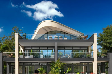Großes, Dreistöckiges Modernes Haus mit beiger Fassadenfarbe, Glasfassade und Flachdach in Sonstige
