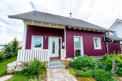 Foto de fachada de casa roja escandinava pequeña de dos plantas con revestimiento de madera, tejado a dos aguas y tejado de teja de barro