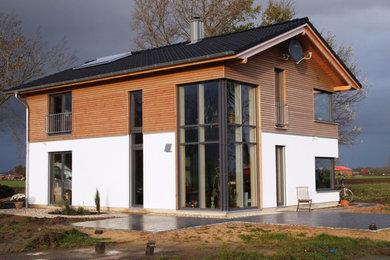 Modelo de fachada de casa marrón actual de tamaño medio de dos plantas con revestimiento de madera, tejado a dos aguas y tejado de teja de barro