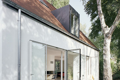 Imagen de fachada de casa blanca actual de tamaño medio de dos plantas con tejado a dos aguas y revestimiento de estuco