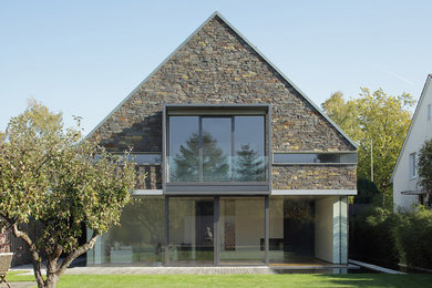 Diseño de fachada actual de tamaño medio de dos plantas con revestimiento de piedra y tejado a dos aguas