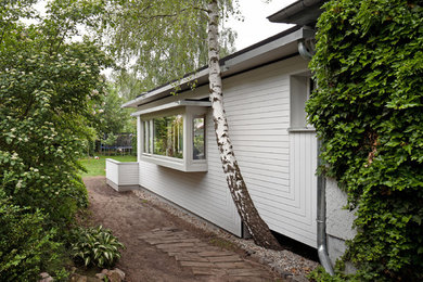 Foto della facciata di una casa bianca a due piani con rivestimento in legno e tetto piano