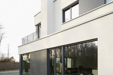 Diseño de fachada blanca actual grande de dos plantas con revestimiento de estuco y tejado plano