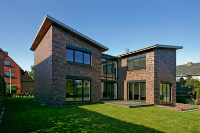 Großes, Zweistöckiges Modernes Einfamilienhaus mit Steinfassade, roter Fassadenfarbe, Pultdach und Ziegeldach in Sonstige
