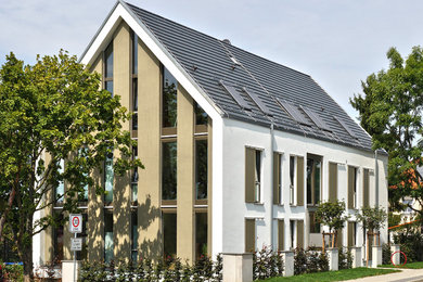 Ejemplo de fachada actual grande de tres plantas con tejado a dos aguas y revestimientos combinados