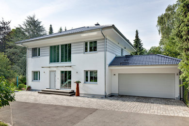 Cette photo montre une façade de maison blanche chic à un étage avec un toit à quatre pans.