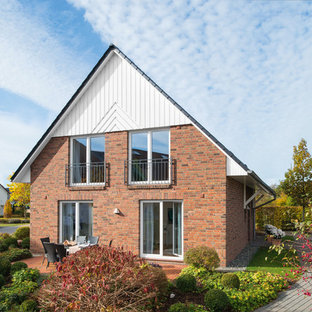 Mittelgroßes, Braunes, Zweistöckiges Landhausstil Einfamilienhaus mit Backsteinfassade, Satteldach und Ziegeldach in Sonstige