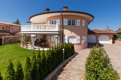 Imagen de fachada de casa beige mediterránea grande de dos plantas con revestimiento de estuco, tejado a cuatro aguas y tejado de teja de barro