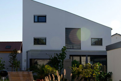 Ejemplo de fachada blanca actual grande de dos plantas con revestimiento de estuco y tejado de un solo tendido