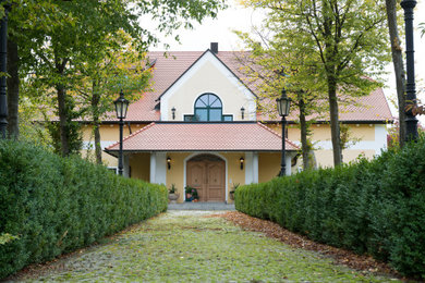 Zweistöckiges Landhaus Haus mit gelber Fassadenfarbe und Ziegeldach in München
