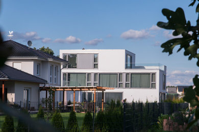 Großes, Dreistöckiges Modernes Einfamilienhaus mit Putzfassade, weißer Fassadenfarbe und Flachdach in Berlin