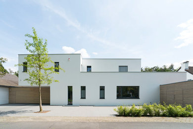 Inspiration for a medium sized and white modern two floor render detached house in Dusseldorf with a flat roof.