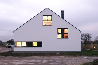 Großes, Dreistöckiges Modernes Einfamilienhaus mit Putzfassade, weißer Fassadenfarbe und Satteldach in Sonstige