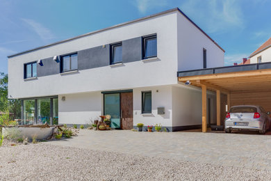 Aménagement d'une grande façade de maison blanche contemporaine en stuc à un étage avec un toit plat et un toit végétal.