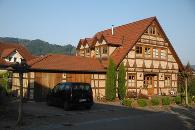 Esempio della facciata di una casa marrone country a due piani di medie dimensioni con tetto a capanna e rivestimento in pietra