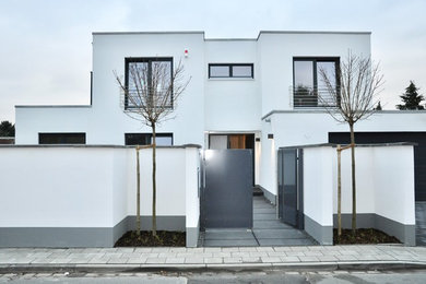 Mittelgroßes, Zweistöckiges Modernes Haus mit Putzfassade, weißer Fassadenfarbe und Flachdach in Düsseldorf